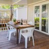 Terrazza con tavolo, sedie bianche e una bottiglia di vino.
