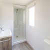 Bagno moderno con doccia in vetro, lavabo e pavimento in legno chiaro.
