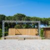 Palco all'aperto con struttura metallica, pavimento in mattoni e capanno vicino.