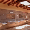 Bagni pubblici con diverse lavandini e specchi, sotto un soffitto con travi in legno e lucernari.