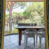 Tavolo e sedie su un balcone, viste su alberi e natura attraverso tende aperte.