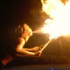 Una donna sputa fuoco da due torce accese in un ambiente oscuro.