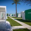 Complesso di moderni bungalow bianchi e verdi con sentieri e palme.