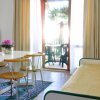 Soggiorno con tavolo, sedie gialle, divano beige e uscita verso un balcone.