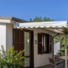 Esterno di una casa con veranda, sedie, piante e cielo sereno.