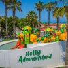 Parco giochi acquatico con scivoli colorati e palme.