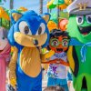 Mascotte colorate posano insieme davanti a giochi d'acqua in un parco acquatico.