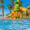 Un parco acquatico con scivoli colorati e palme sullo sfondo.