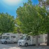 Un'area di sosta per camper con veicoli parcheggiati sotto alberi verdi.