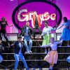 Performance teatrale di Grease con costumi anni '50 su un palco.