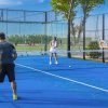 Quattro persone giocano a padel su un campo blu all'aperto.