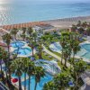 Resort con piscine e palme vicino alla spiaggia, mare scintillante.