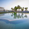 Piscina con decorazione marina e lettini blu, circondata da palme.