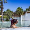 Persone rilassate in una piscina con fontana decorativa a tema marino.