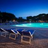 Piscina illuminata con lettini vuoti al tramonto.