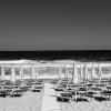 Spiaggia in bianco e nero con ombrelloni chiusi.