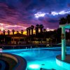 Piscina illuminata di notte con cielo colorato.