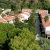 Villaggio turistico con tetti rossi, circondato da alberi.