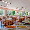 Interno di un ristorante con tavoli apparecchiati e finestre aperte su un giardino.