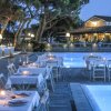 Tavoli apparecchiati vicino a una piscina illuminata al tramonto.
