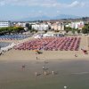 Spiaggia affollata con ombrelloni colorati, mare e edifici sullo sfondo.