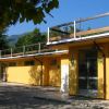 Edificio giallo con terrazza e cancellata in un giorno soleggiato.