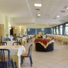 Ampia sala da pranzo con tavoli apparecchiati e sedie blu.