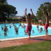 Persone in una piscina che seguono istruttori a bordo vasca.
