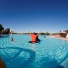 Piscina con un adulto su un gonfiabile e un bambino che nuota.