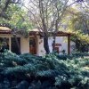 Una piccola casa tra gli alberi e cespugli verdi.