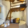 Interno di una casa con cucina, letto e soppalco in legno.