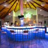 Un bar moderno con bancone retroilluminato, sedie alte e tetto in legno.