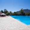 Piscina grande con pavimento in pietra, vista su montagne e cielo blu.
