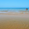 Spiaggia con mare calmo e bagnanti in lontananza.