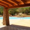 Vista di una piscina da un portico con colonne in pietra e tetto in legno.