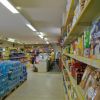 Interno di supermercato con file di prodotti alimentari e acqua.