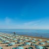 Spiaggia con file di ombrelloni verdi e bianchi.