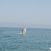 Una persona fa windsurf su un mare calmo sotto un cielo sereno.