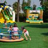 Bambini giocano su una giostra e scivoli gonfiabili in un parco giochi.
