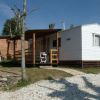 Una casa mobile bianca con veranda in legno e sedia.