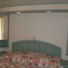Una testiera curva di legno verde con specchi laterali sopra un letto con copriletto patchwork.
