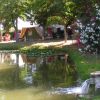 Una tenda campeggio vicino a un laghetto con fiori e alberi.