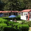 Casette con tetto rosso, persone e ombrelloni in giardino.