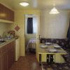Interno di una roulotte con angolo cottura, sala da pranzo e letto in fondo.