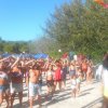 Un gruppo di persone fa esercizi all’aperto sotto un cielo azzurro.
