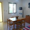 Sala con tavolo e sedie, divano colorato, TV su frigorifero e una finestra.