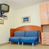 Stanza con divano blu, TV sospesa e armadio.