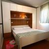 Camera da letto con letto matrimoniale, armadio bianco e finestra con tenda a quadri.