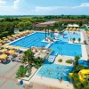 Piscina con scivolo, ombrelloni gialli e verde intorno.