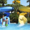 Una piscina con scivoli blu e gialli e persone che giocano.